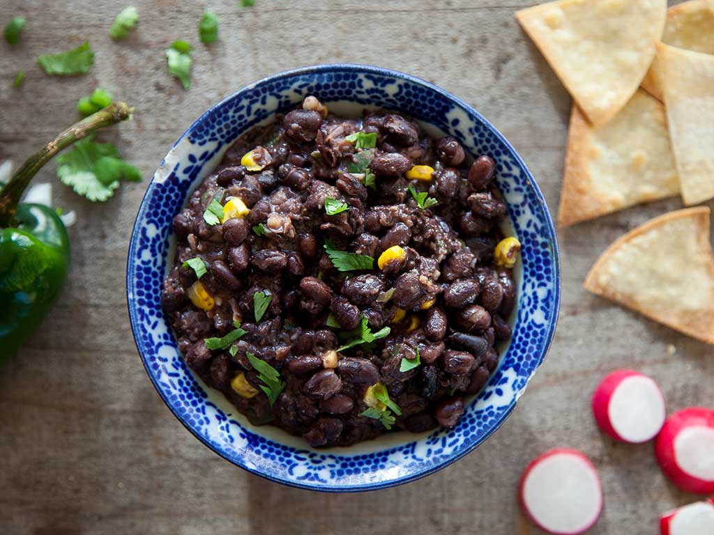 Blue bowl filled with black bean dip and sprinkled with cilantro